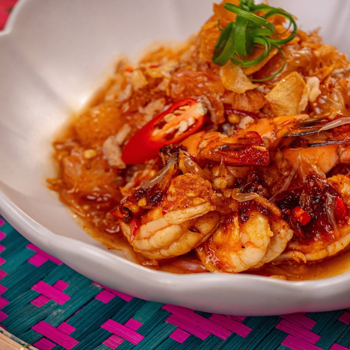 A shrimp dish topped with crisp shallots and chili